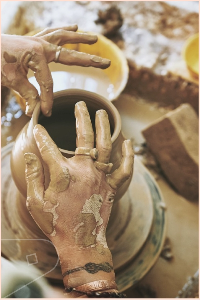 Messy potters hands making a vase in their pottery studio